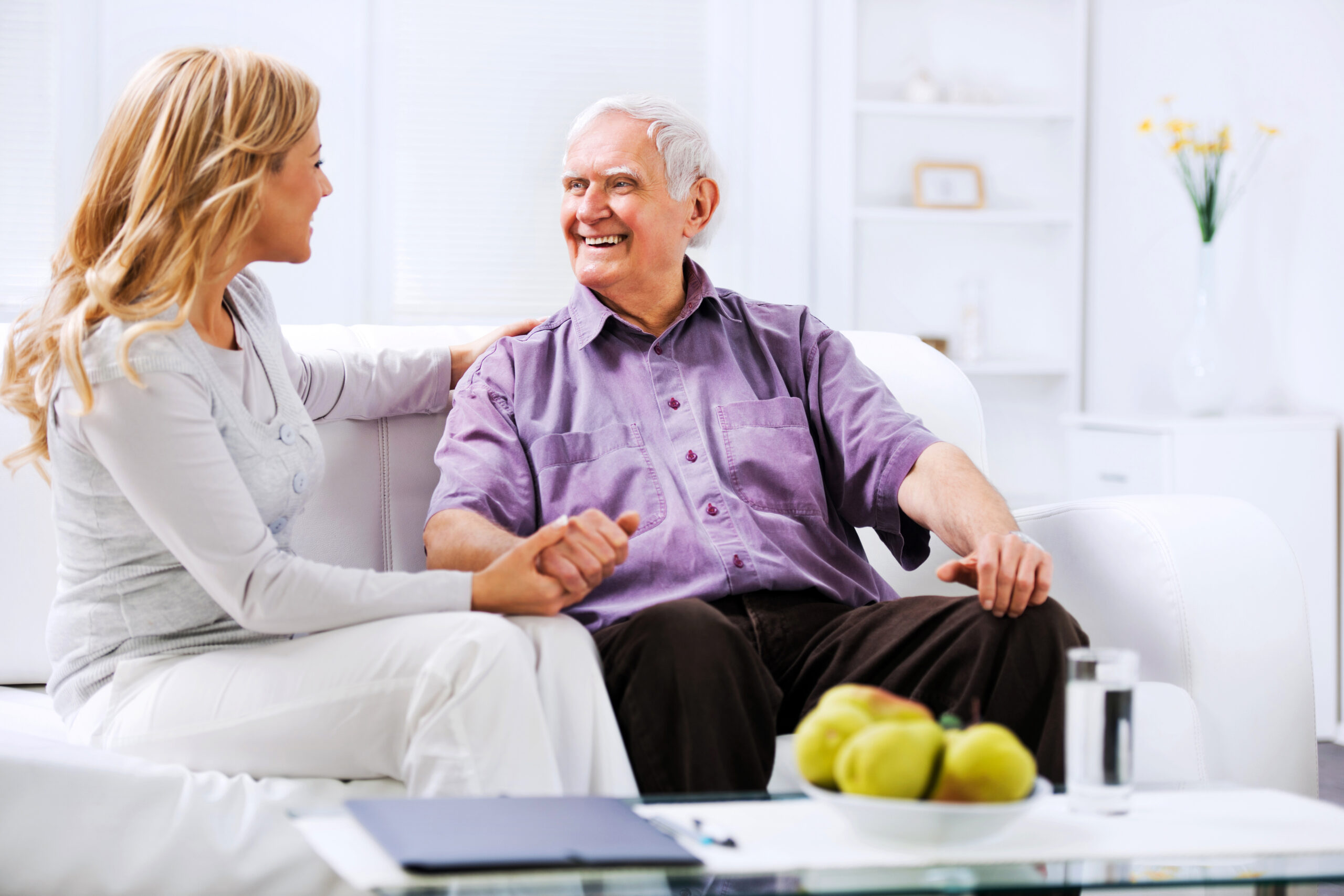 Home caregiver sitting n the sofa with an elderly man